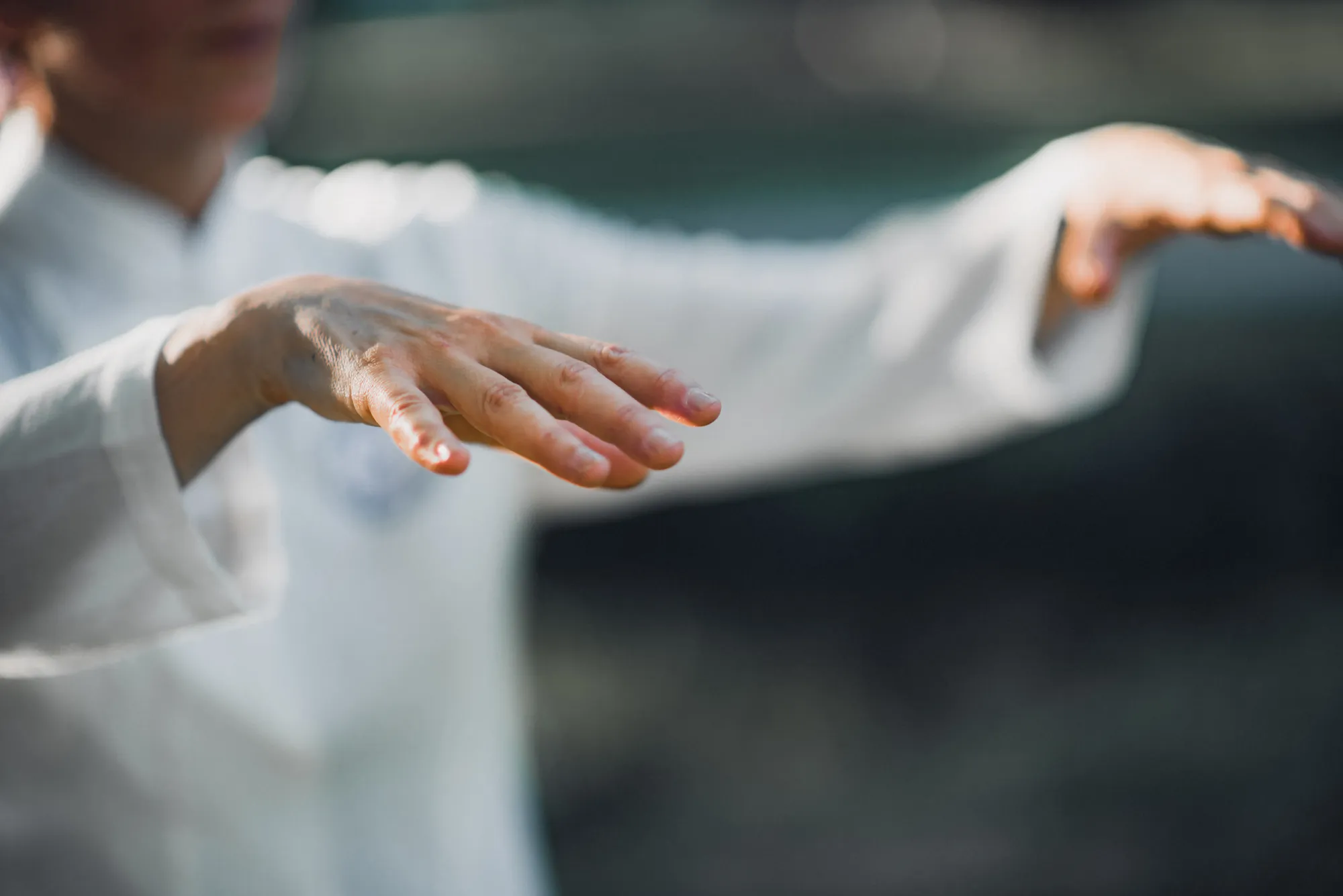 Blurred close-up of fluid hand movements in a white traditional Qi Gong uniform.