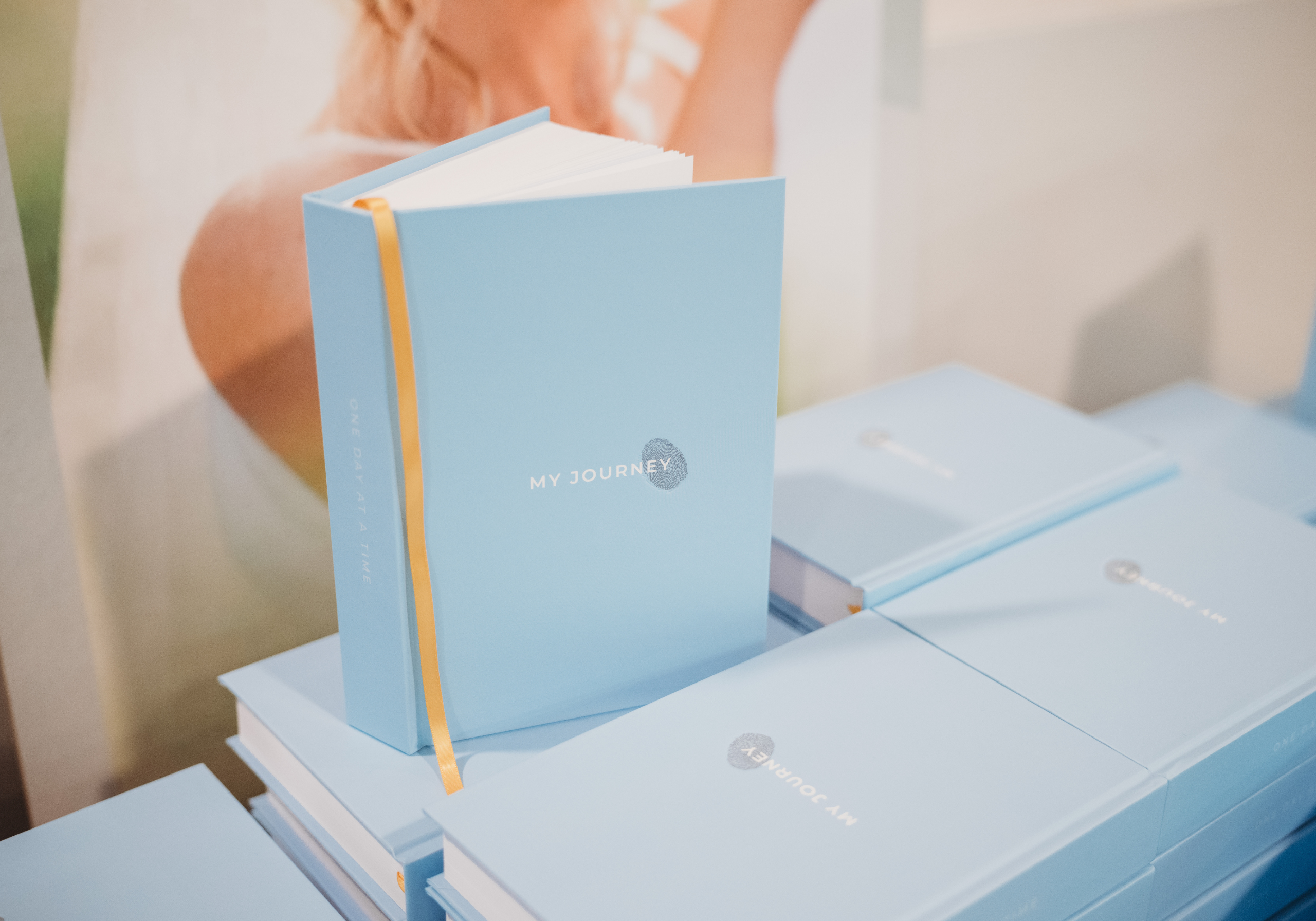 Table of light blue My Journey Wellness Journals with bright yellow ribbon.